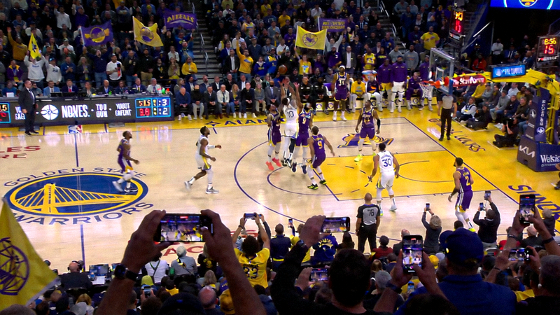 NBA常规赛洛杉矶湖人对阵金州勇士的比赛现场画面，双方球员在球场上激烈对抗，观众席座无虚席